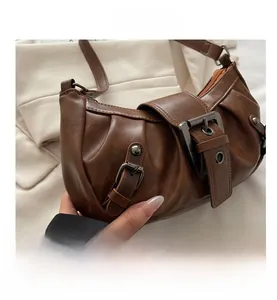 Detail of caramel brown faux leather shoulder bag with pleated texture and metal buckle