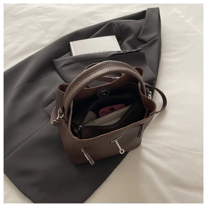 Detailed view of brown litchi grain leather bucket bag with internal zipper pocket