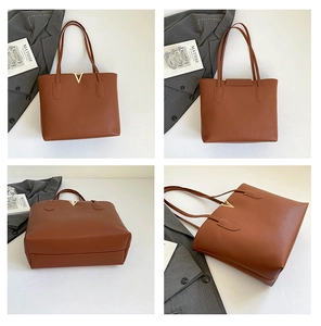 Detail view of the brown leather tote bag with lychee grain texture and gold V-shaped metal logo