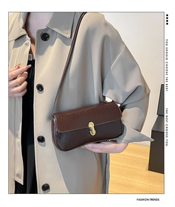 Close-up of a dark brown glossy PU leather handbag with elegant gold metal buckle detail