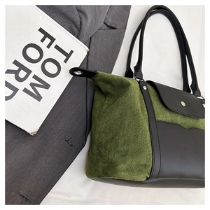 Detail of green suede tote bag with black leather straps and metal buckle front pocket