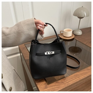 Detail of black lychee grain leather bucket bag with silver twist lock and shoulder strap