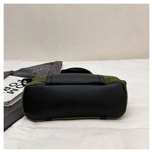 Detail view of the olive green textured fabric base and black leather trim of the tote bag