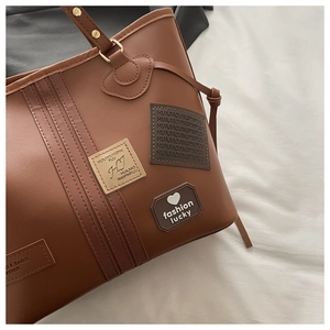 Close-up of brown PU leather tote bag details with embossed logo and golden hardware