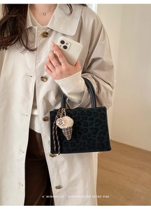 Detail of leopard print handbag featuring ice cream charm and striped ribbon accent
