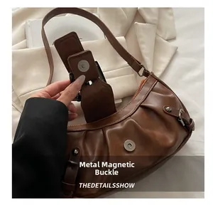 Detail of the magnetic metal snap closure on a pleated brown retro hobo shoulder bag