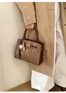 Détail d'un sac à main en daim marron avec texture verticale et fermoir tournant en métal doré