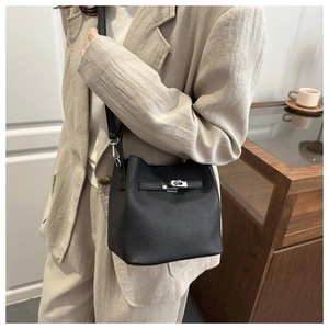 Detail of black pebbled leather bucket bag with silver turn-lock and adjustable strap
