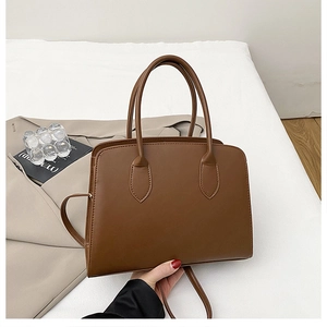 Detail of a brown textured tote bag with double handles and a detachable shoulder strap