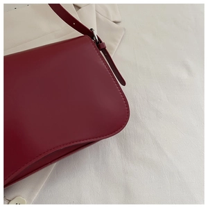 Dettaglio borsa a spalla in pelle bordeaux con patta e finiture in metallo argento