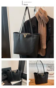 Close-up of black leather tote bag featuring lychee texture and golden V-shaped metal buckle