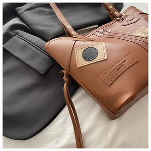 Detail of a brown PU leather tote bag with vintage stitched patches and fashion branding