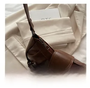 Close-up of smooth bronze zipper and pleated leather detail on a brown vintage handbag