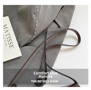 Detail of comfortable dark leather handle on gray fabric bag with white contrast stitching