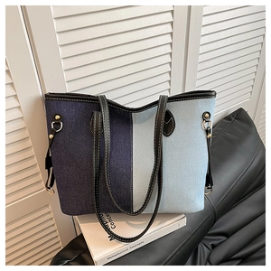 Detail of blue denim patchwork tote bag featuring black leather trim and white stitching