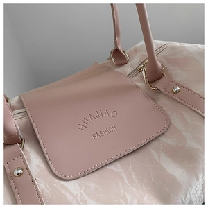 Detail of pink marble pattern handbag featuring engraved logo and gold hardware