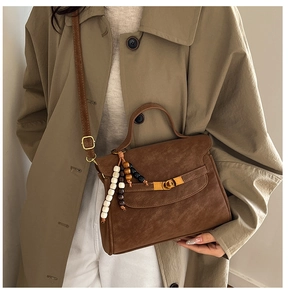 Close-up of brown vintage tote bag with gold swivel clasp and colorful wood bead charm