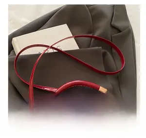 Detailed macro view of bright red patent leather quilted handbag with golden metal hardware