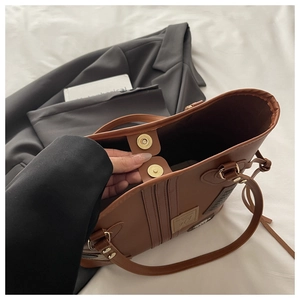 Detail of brown tote bag showing dual magnetic snap closures and premium faux leather texture