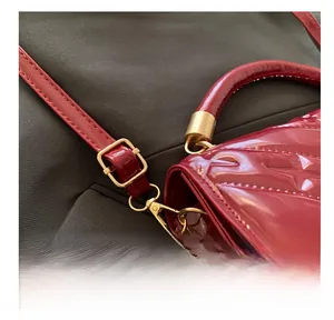 Close-up of red patent leather embossed texture with gold metal buckle and strap hook
