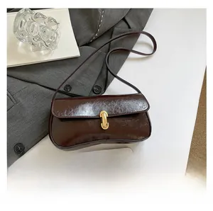 Detail of dark brown glossy underarm bag showing size capacity next to a smartphone
