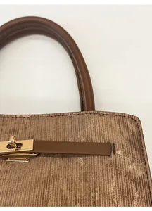 Close-up of vintage bucket bag featuring vertical stripes and a gold metal twist lock