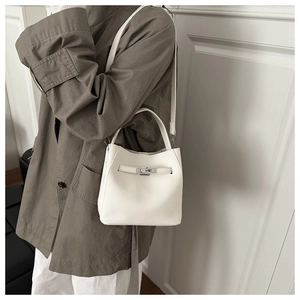 Close-up of white lychee leather bucket bag with silver turn-lock and crossbody strap