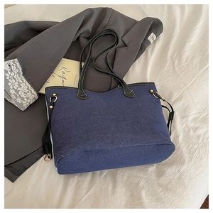 Detail of blue denim tote bag with black faux leather strap and contrast stitching