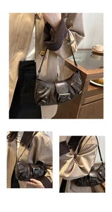 Close-up of vintage brown underarm bag showing gathered pleats and wide metal buckle