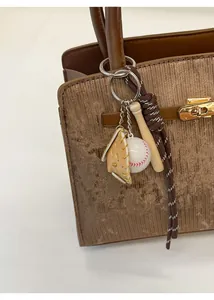 Detail of sports-themed keychain with mini baseball bat on leather bag handle