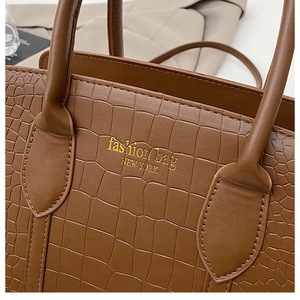 Dettaglio ravvicinato della borsa marrone a coccodrillo con scritte New York oro