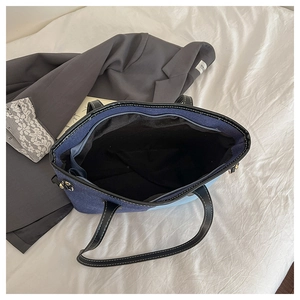 Detailed interior view of a color-block denim tote bag with zipper and black lining