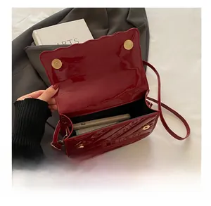 Detail of red patent leather crossbody bag showing wave flap and spacious interior