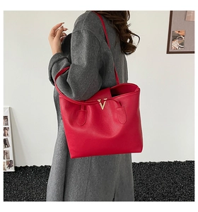 Detailed shot of large red pebbled leather tote bag with gold V hardware detail