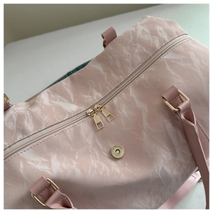 Macro detail of marble print travel bag featuring gold hardware and zipper closure