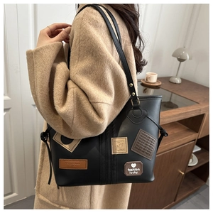 Detail of black PU leather tote bag with vintage heart patches and decorative stitching