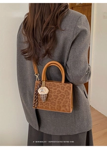 Detail shot of leopard print crossbody bag with ice cream pendant and silk scarf charm