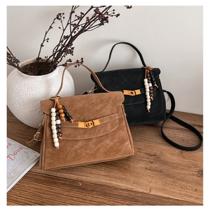 Detail of vintage suede crossbody bags with wooden bead tassels and metal turn-lock closure