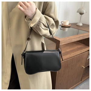 Primo piano della borsa sottobraccio in pelle nera opaca con bordo ondulato unico