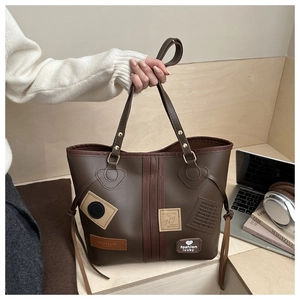 Detail of dark brown PU leather tote bag with vintage patches and fashion lucky lettering
