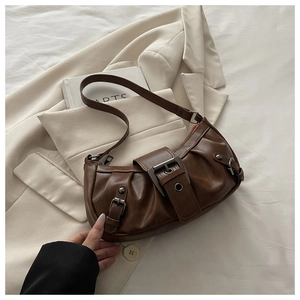 Close-up of vintage brown tote bag featuring silver buckles and pleated faux leather detail