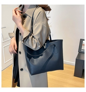 Close-up of black litchi grain leather tote bag featuring a polished silver V-shaped buckle