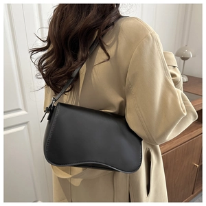 Borsa a spalla minimalista nera in similpelle lucida con base ondulata indossata