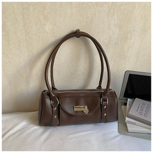 Détail d'un sac bowling marron foncé avec pendentif en cœur et rivets métalliques