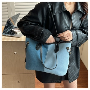 Detail of color-block denim tote bag with black leather handles and gold metal studs