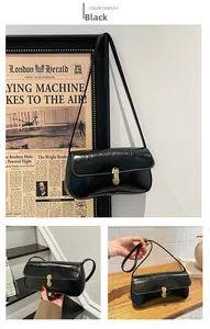 Detailed macro of the glossy black baguette bag with elegant golden metallic buckle closure
