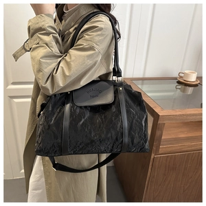 Detail of black textured large capacity travel tote bag shown on a model's shoulder