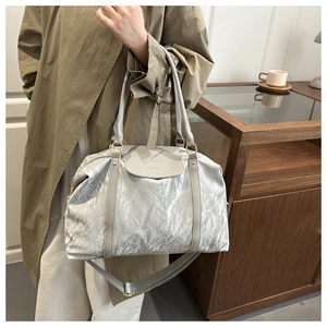 Detail of silver tote bag showing crinkled metallic texture and brand logo engraving