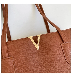 Detail of brown lychee grain leather tote bag with elegant gold V-shaped metal hardware