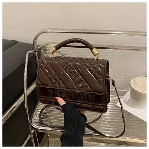 Detail of dark brown patent leather handbag with embossed FASHION lettering and star